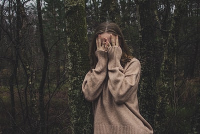 女人穿着棕色的毛衣站在森林
